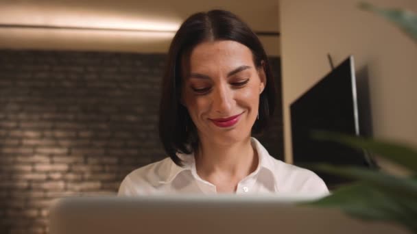 Portrait d'une jolie femme caucasienne souriante travaillant sur un ordinateur portable. Femme heureuse pigiste travaillant sur la dactylographie d'ordinateur portable et regardant le moniteur au bureau à la maison. Travail indépendant à distance sur le lieu de travail — Video