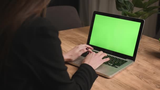Крупный план. Вид сзади. Кавказская деловая женщина работает на ноутбуке зеленый экран хромаки в домашнем офисе. Девушка руки набрав на ноутбуке зеленый экран и уйти в замедленной съемке. Женщина-фрилансер пишет письмо — стоковое видео