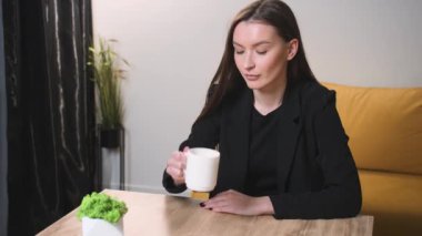 Ev ofisinde çay içen tatmin olmuş bir iş kadını. Çekici bir kadın evinde ağır çekimde kahve içiyor. Sabahları elinde çay tutan gülümseyen bir kadın.