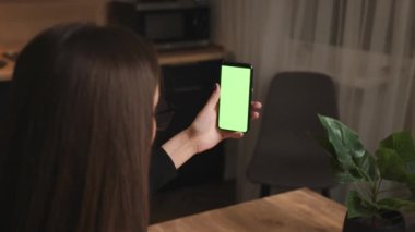 Arkadan bak. Görüntülü konuşma yapan bir kadın yeşil ekran akıllı telefonu. Çevrimiçi görüntülü konuşmalar yapan telefon kullanan bir kadın. 