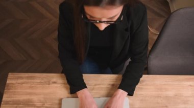 Kapatın. Üst Manzara. Kafkasyalı iş kadını dizüstü bilgisayarla çalışıyor. Dizüstü bilgisayarda yavaş çekimde yazan kız elleri. Kapalı kapılar ardında ofis bilgisayarına mektup yazan serbest çalışan bir kadın var..