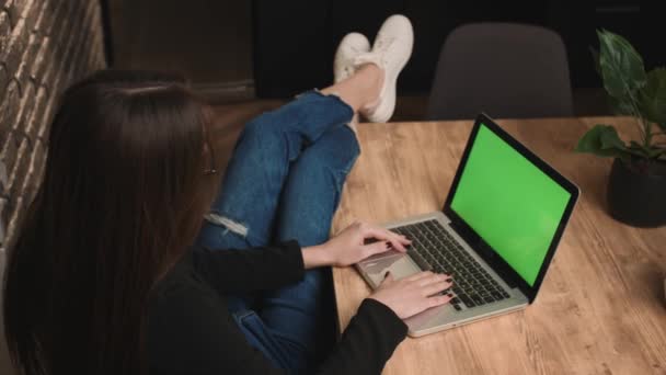 Vrouw op zoek naar laptop met groene scherm mockup, ontspannen thuis. Freelancer kijken op monitor display met groen scherm, chromakey. — Stockvideo