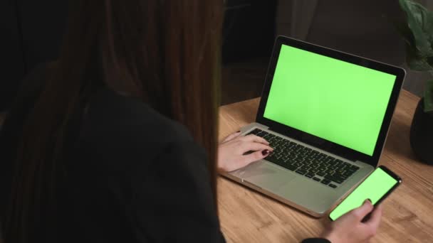 Yakın plan kadın, telefon Chromakey 'i olan yeşil ekranda dizüstü bilgisayarda yazı yazıyor. Cep telefonunun yeşil ekranını tutan kadınların ellerini yakın plan çek.. — Stok video