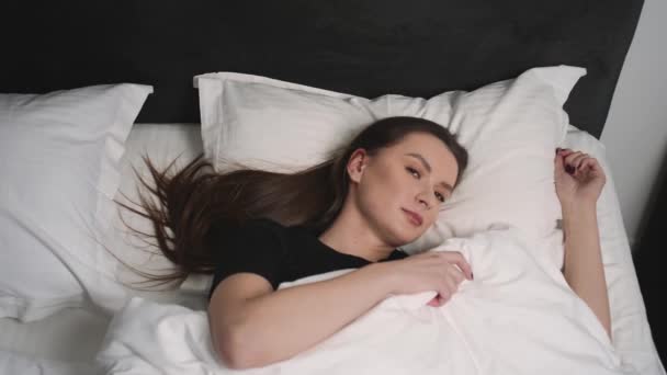 Front view of shocked young pretty woman oversleep and getting up fast while lying in bed. — Stock Video