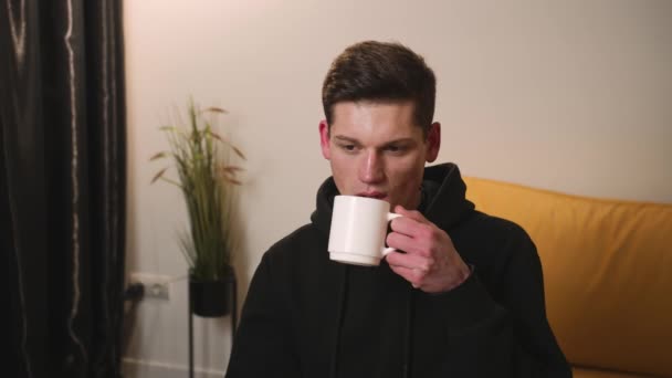 Портрет чоловіка, який п'є каву або чай з білої чашки, відпочиває від роботи. Кавказький чоловік п'є ранкову каву вдома... — стокове відео