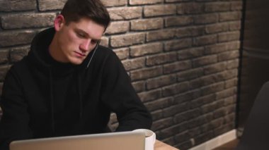 Telefonu kapatan adam, dizüstü bilgisayarı kullanan adam, yeni başlatılan projeyi tartışan, arkadaşla konuşan, merkez ofisten çalışan.