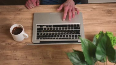 Kapatın. Üst Manzara. Laptopta çalışan beyaz bir adam. Adam elleri dizüstü bilgisayarda yavaş çekimde yazıyor. Ev ofisindeki dizüstü bilgisayarı kullanarak serbest çalışan adamı kapat..