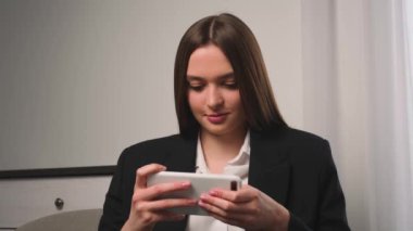 Genç bir kadının portresi evde ya da ofiste cep telefonuyla oyun oynuyor. Akıllı telefon oyunlarından hoşlanan çekici bir kadın.