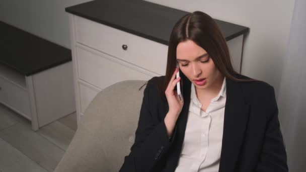 O femeie de afaceri supărată vorbind la birou. Fata vorbind telefon pe canapea. Femeia nemulțumită face apel telefonic în mișcare lentă . — Videoclip de stoc