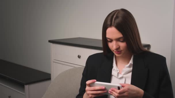 Retrato de mujer joven juega juego móvil en el teléfono en casa u oficina. Mujer atractiva disfrutando de los videojuegos de teléfonos inteligentes y perdió el juego. — Vídeo de stock