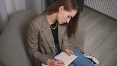 Kafkasyalı güzel bir kadın telefonla konuşuyor, not defterine notlar yazıyor. Ev ödevi. İş kadını notlar yazıyor..