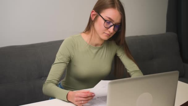 Žena v brýlích pracuje s notebookem, on-line dálkové vzdělávání, videohovory konference. Studentky studují doma s papírovým dokladem.. — Stock video