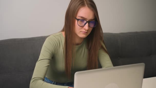 Vermoeide blanke vrouw met bril chatten op laptop, surfen op internet social media studeren of online werken thuis — Stockvideo