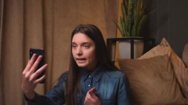 Kızgın Kadın evdeki kanepede konuşurken video görüşmesi yapıyor. Sinirli kadın video görüşmesi yapıyor, ofisteki ekiple çevrimiçi görüşme yapıyor..