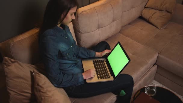 ラップトップの緑の画面のクロマキーを見て笑顔の女性,コンテンツや映画を見て,インターネットを閲覧,自宅のオフィスで勉強や仕事. — ストック動画