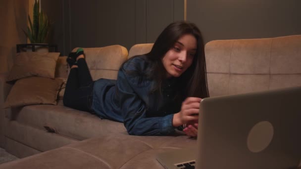 Gelukkig vrouw lachen heeft video gesprek chatten op laptop liggend op bank thuis. — Stockvideo