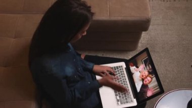 Üst Manzara. Güzel, gülümseyen bir kadının bilgisayarında arkadaşlarıyla görüntülü konuşma yapması. Mutlu Kadın, evdeki video görüşmelerinde iş arkadaşlarıyla iletişim kuruyor..