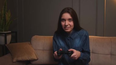 Evde video oyunu oynayan bir kadın. Kanepede oturup video oyunu oynayan heyecanlı oyuncu kadın..