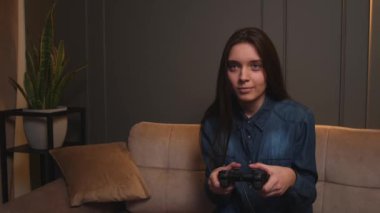 Evde video oyunu oynayan bir kadın. Kanepede oturup video oyunu oynayan heyecanlı oyuncu kadın..