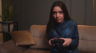 Evde video oyunu oynayan bir kadın. Heyecanlı oyuncu kadın koltukta otururken oyunu kaybetti..
