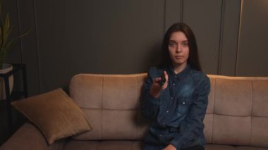 Uzaktan kumandalı bir kadın en sevdiği mizah programını arıyor rahat koltukta rahat bir şekilde oturuyor..