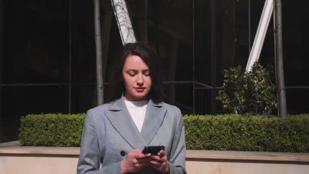 Mulher muito sorridente digitando no telefone na rua. — Vídeo de Stock