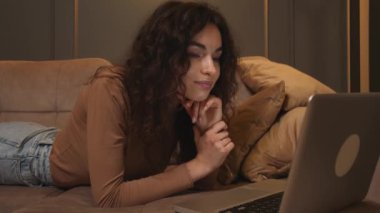 - Yakın çekim. Genç bir kadının portresi kanepede dizüstü bilgisayar kullanarak yatar, internette gezinir sosyal medyada çalışır ya da internette çalışır..