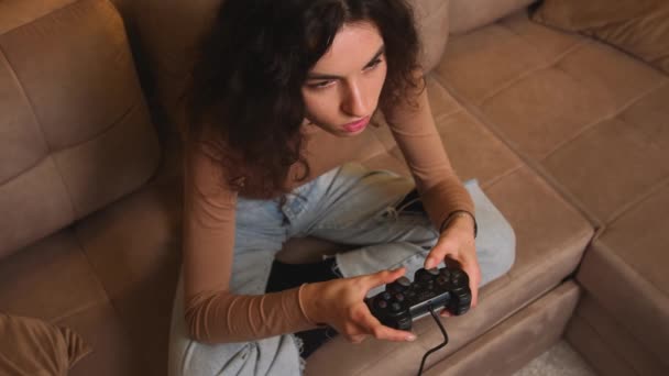 Primo piano. Ritratto di donna che gioca a un videogioco a casa. Emozionato giocatore donna seduta su un divano, giocare ai videogiochi su. — Video Stock