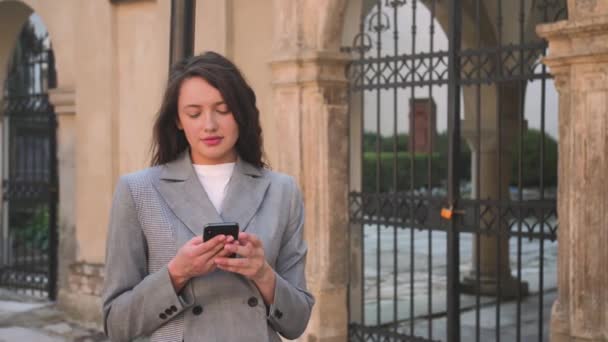 Bella donna sorridente digitando al telefono per strada. — Video Stock