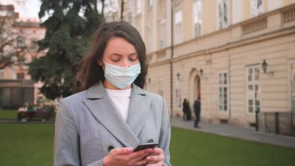 Porträtt av kvinna i medicinsk mask i ansiktet, kvinna som använder telefon på gatan. Epidemi, lunginflammation, hygien. Pandemi — Stockvideo