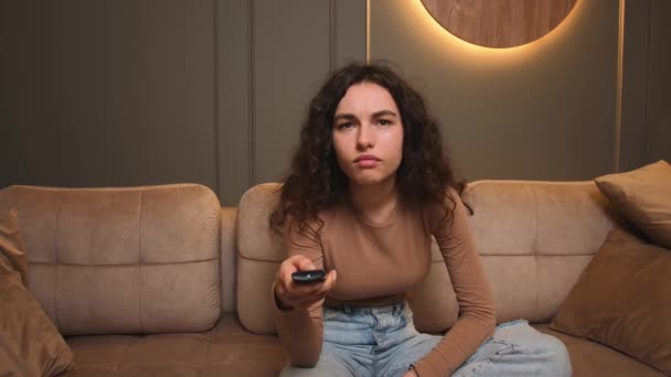 Korku filmi izleyen genç bir kadın, korku dolu bir duygu, oturma odasındaki kanepede oturuyor.. — Stok video