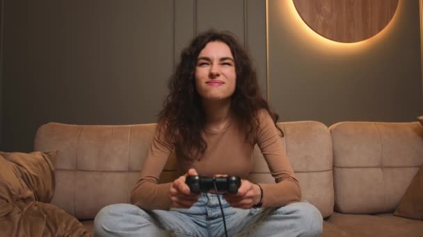 Mujer sonriente jugando un videojuego en casa. Emocionada mujer gamer sentado en un sofá, jugando un juego en el controlador de joystick. — Vídeos de Stock