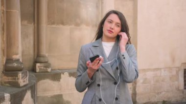 Beyaz tenli çekici iş kadını sokakta kulaklık takıyor..