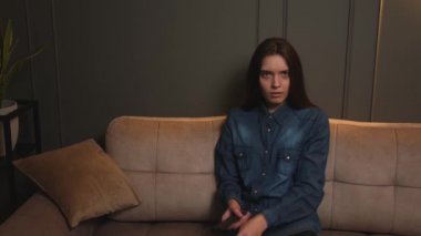 Oturma odasında kanepede oturan genç ve güzel bir kadın korku filmi ya da korkunç haberler izliyor..