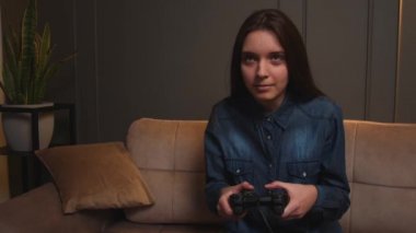 Evde video oyunu oynayan bir kadın. Kanepede oturup video oyunu oynayan heyecanlı oyuncu kadın..