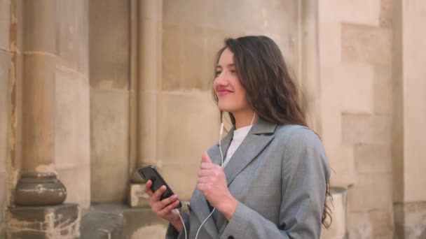Γυναίκα με ακουστικά που ακούει μουσική στο δρόμο και χορεύει. — Αρχείο Βίντεο