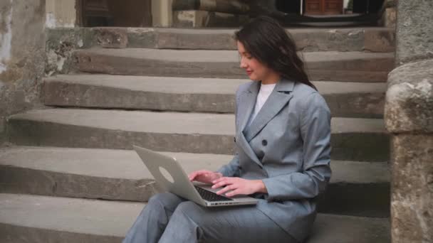 Jovem mulher sentada nas escadas ao usar laptop na rua. — Vídeo de Stock