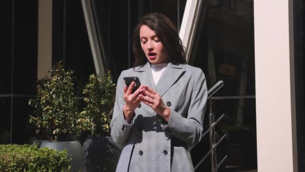 Donna felice usando il telefono, donna ha buone notizie, celebra la vittoria in strada. — Video Stock