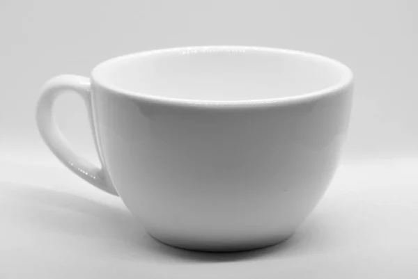 Белая чашка на светлом фоне с выборочной фокусировкой — стоковое фото