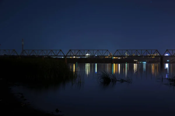 Vue du pont ferroviaire sur la rivière Dnipro la nuit sur fond de lumières de la ville de Kiev — Photo