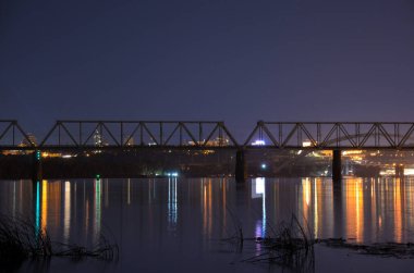 Gece Dnipro nehrinin üzerindeki demiryolu köprüsünün görüntüsü Kyiv 'deki şehir ışıklarının arka planında.