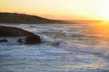 Kıbrıs 'ta deniz dalgaları ve gün batımı. Tatlisu bölgesi.