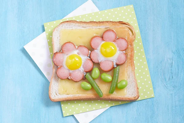 Funny toast with cheese, sausages, quail eggs and edamame — Stock Photo, Image