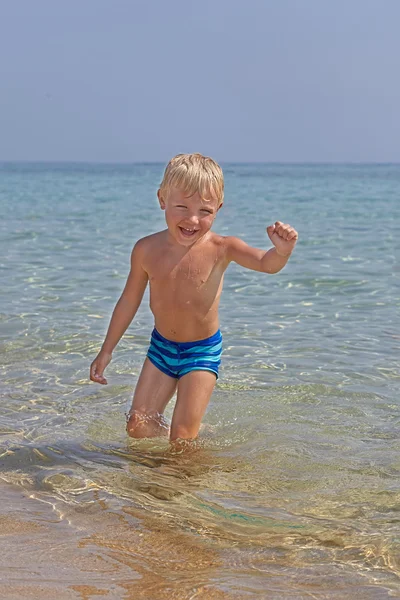 Garoto feliz jogando em uma praia — Fotografia de Stock