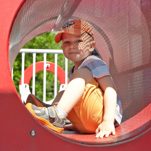 Söt pojke spelar i tunneln på lekplats — Stockfoto