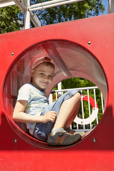 Söt pojke spelar i tunneln på lekplats — Stockfoto