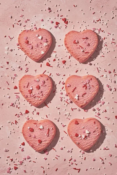Biscoitos decorados em forma de coração no fundo rosa — Fotografia de Stock