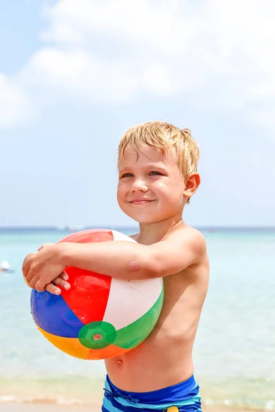 Menino segurando bola de praia colorida na praia desfrutando de férias de verão — Fotografia de Stock