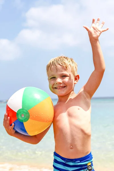 Αγόρι κρατώντας πολύχρωμη μπάλα παραλία στην παραλία απολαμβάνοντας τις καλοκαιρινές διακοπές — Φωτογραφία Αρχείου