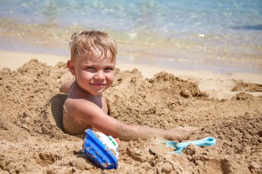 Kumsalda oynayan bir çocuk.